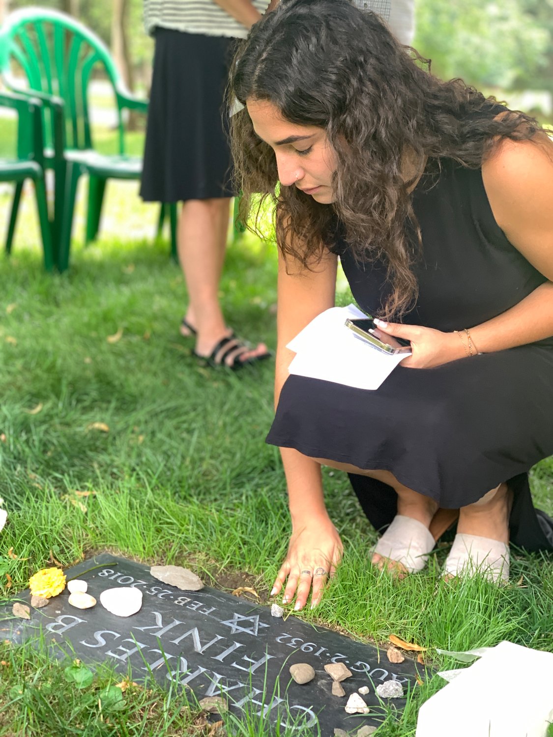 Julia places a pebble on her grandfather’s grave at the unveiling.